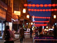 a group of people are walking down a street at night